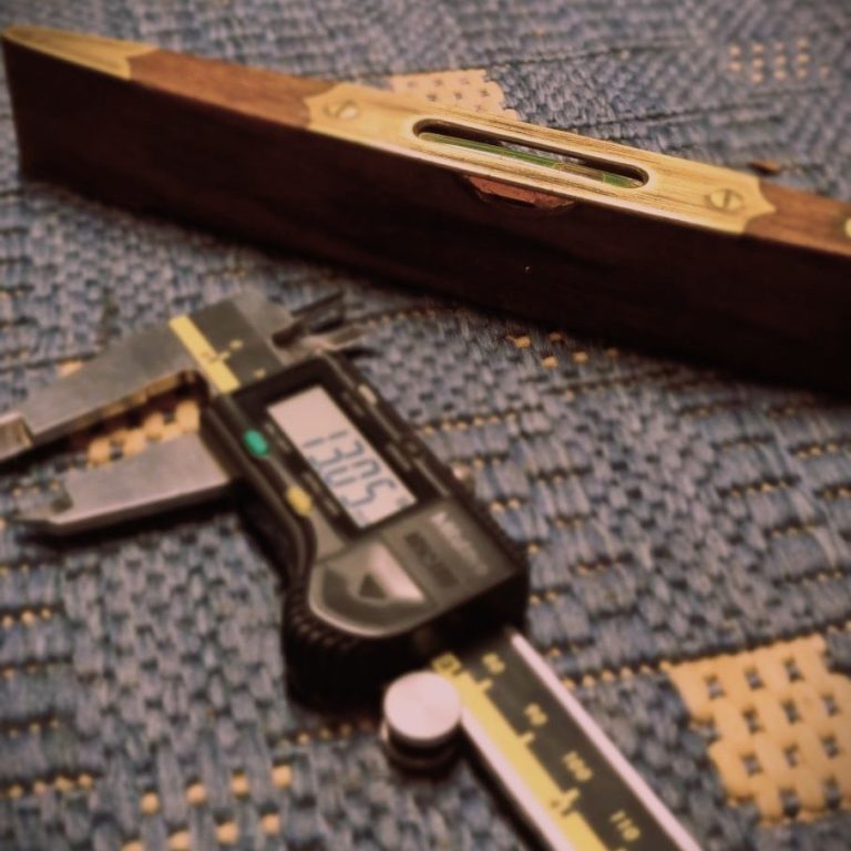 A digital caliper and a level tool on a textured surface.