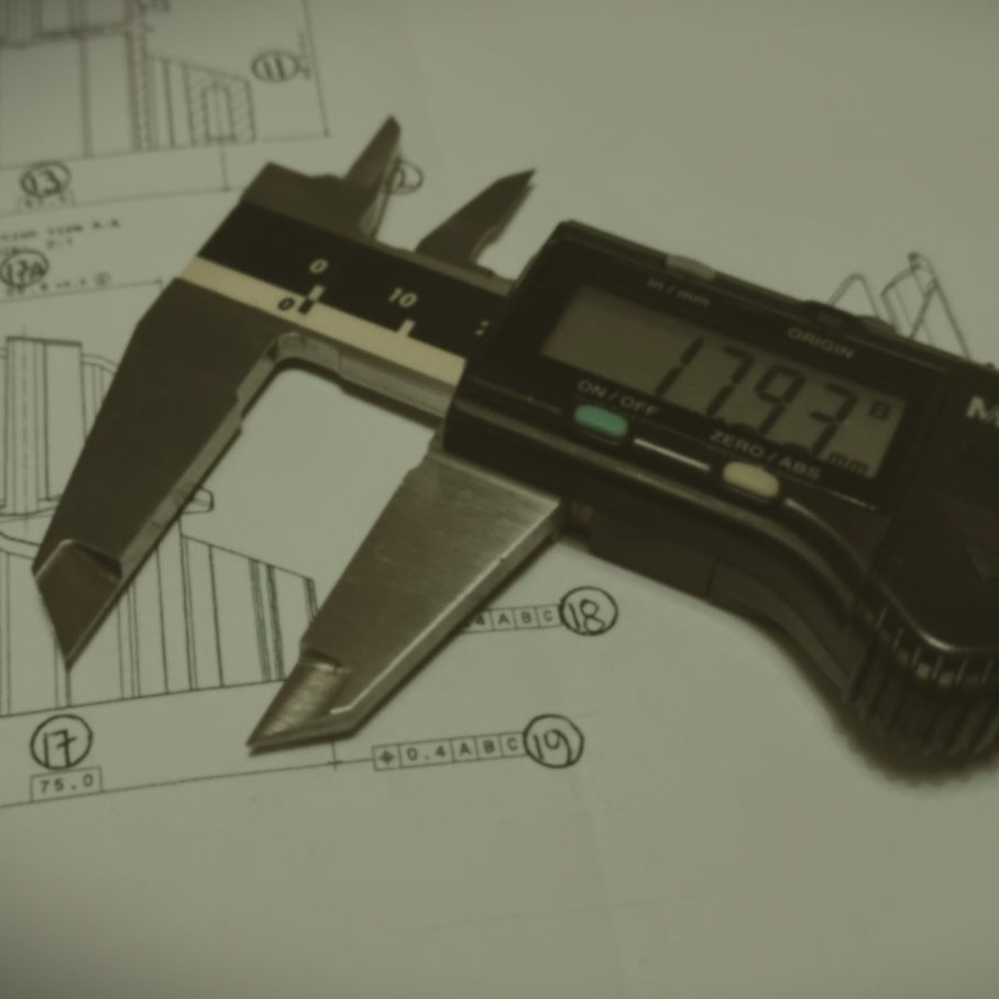 Digital vernier caliper measuring dimensions on engineering drawings.